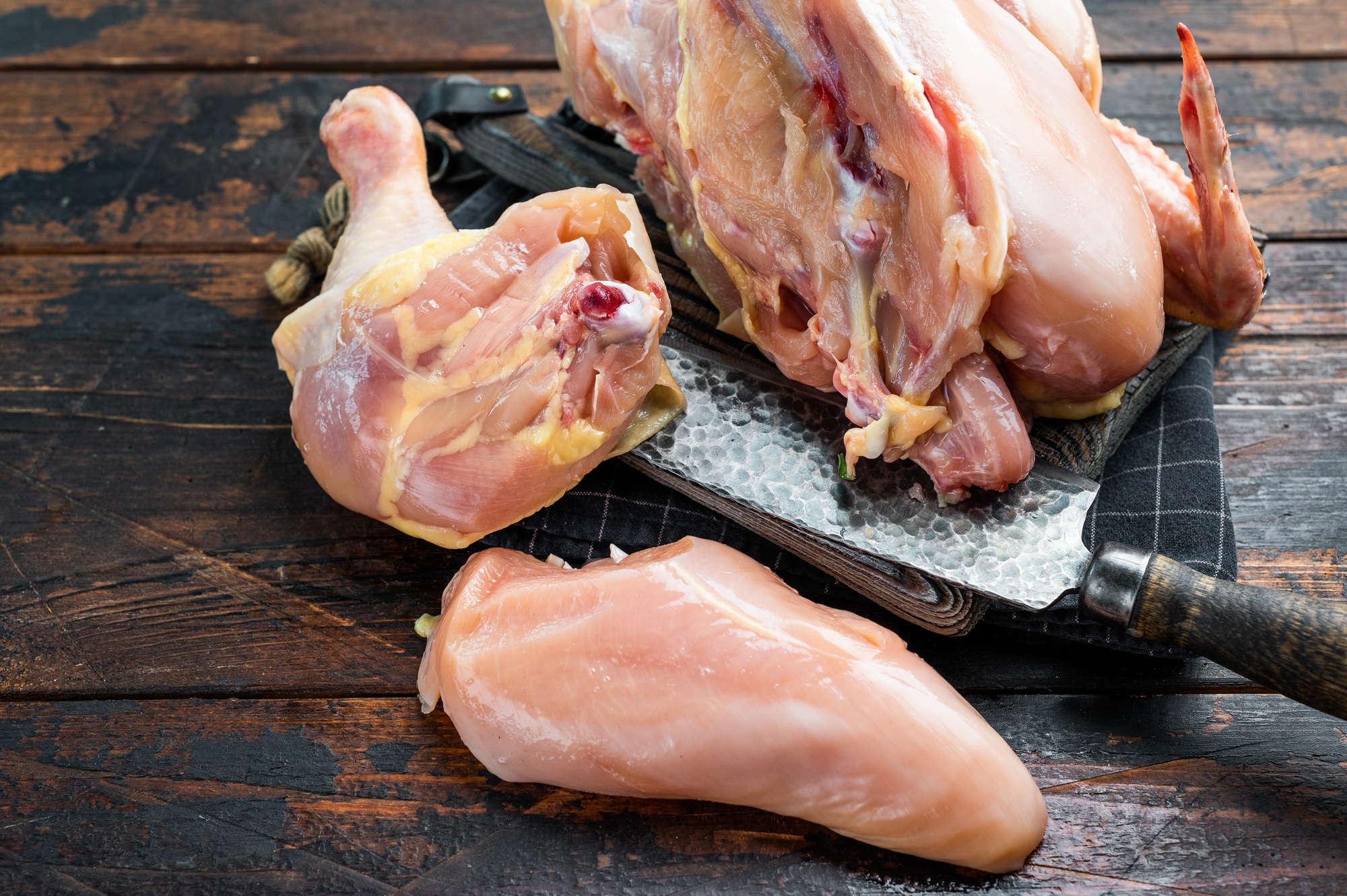 Raw chicken pieces on a wooden cutting board